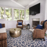 home enclosed porch with wicker chairs, ottoman, TV and fireplace
